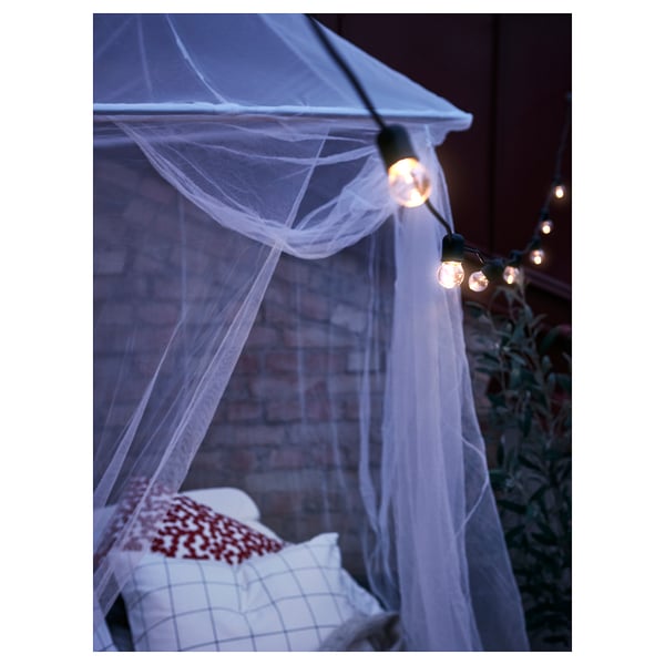 A cozy indoor hammock tent, SOLIG, illuminated by warm string lights, providing a relaxing space.
