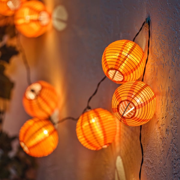 String of round orange lantern lights, perfect for outdoor use, emitting a warm glow.