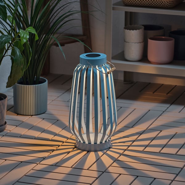 Solar-powered lantern on patio, casts sunray light patterns, auto-on at dusk.