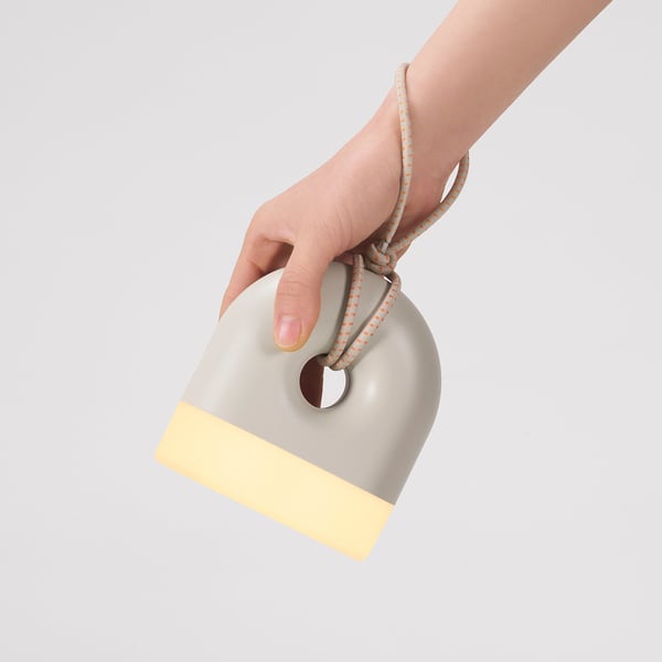 Hand holds battery-powered SOLVINDEN lamp, resembling a donut, suitable for indoor and outdoor use.