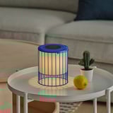A blue SOLVINDEN solar-powered lamp on a white table, lit, with a lemon and cactus beside it.