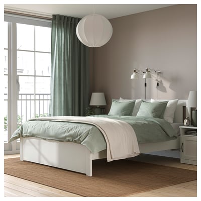 Modern bedroom with white SONGESAND bed, high headboard, window, lamp, calming neutral colours.