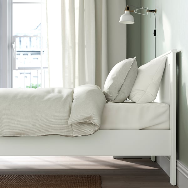 White bed frame with soft edges and high legs, designed for adjustable mattress thickness.