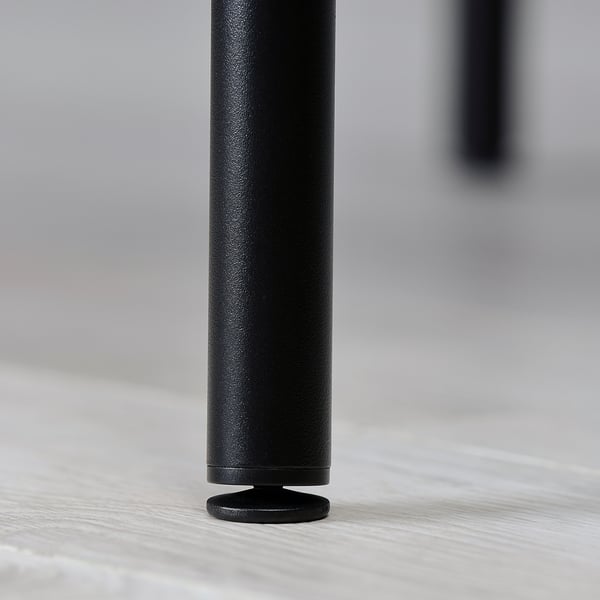 Black metal table leg with rounded base, standing on light wooden floor.