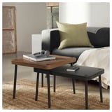 Living room with nesting tables: one holds laptop & headphones, other book & blanket.