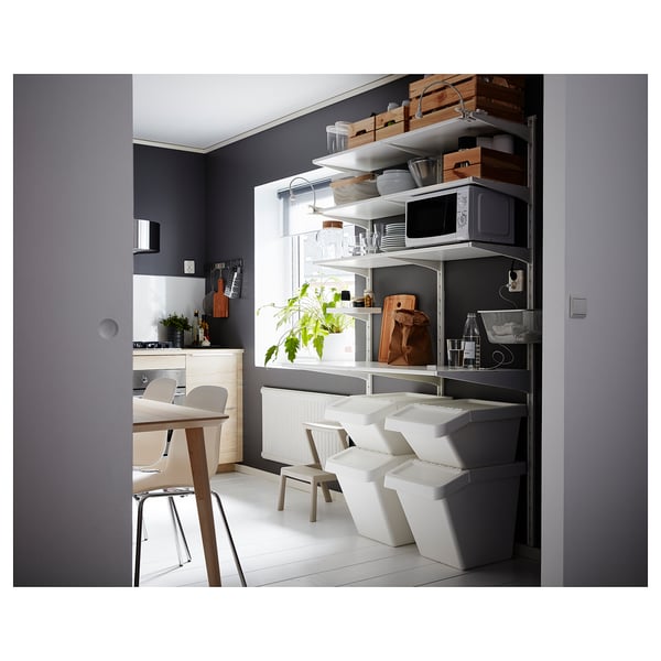 Modern kitchen with white furniture, including stackable SORTERA bins, a microwave, and dining table with chairs, against dark gray walls.