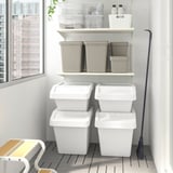 SORTERA bins stacked, some on shelves, others on floor, with a broom.