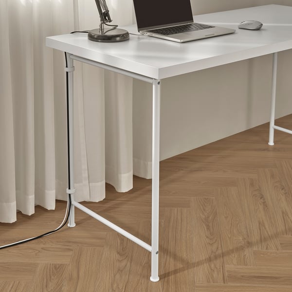 White desk with laptop, mouse, and lamp. Adjustable legs for uneven floors, cord management shown.