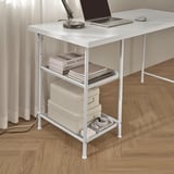 Small white desk with shelves holding books and bins, a laptop, and a lamp, showcasing its organizational.