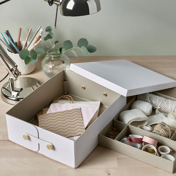 Organized storage box with removable compartments for small items and large base for paper storage.