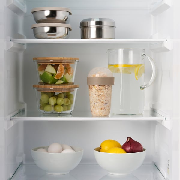 Fridge shelf with snack containers and lemon water pitcher.