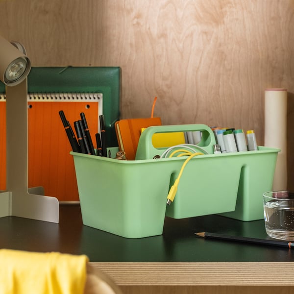 A green STACKSTOD organizer on a desk holding pens, notebooks, and cables. Perfect for desk and hobby accessories.