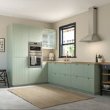 Modern kitchen with STENSUND light green cabinets, stainless steel oven, and large window.