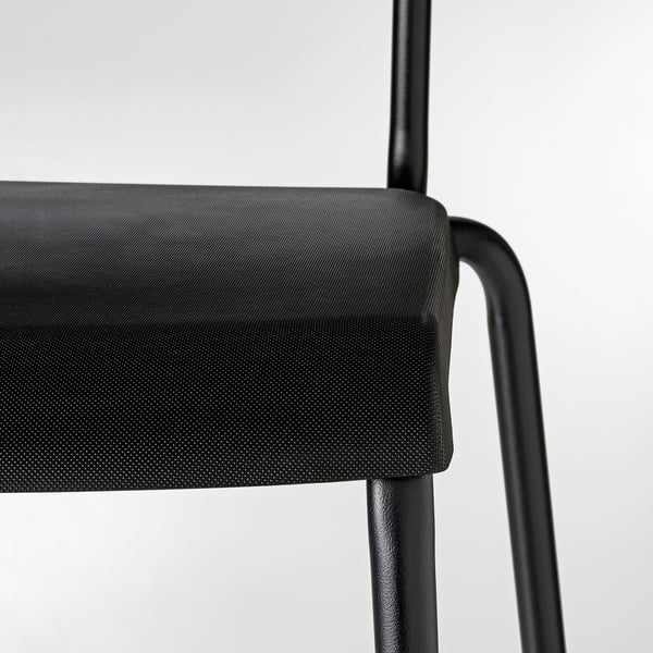 Close-up of modern chairs black frame and perforated seat, showcasing sleek design and robust build.