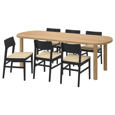 The STOCKHOLM 2025 dining set, including an oval wooden table and six black chairs with woven seats, designed for comfort and durability.