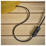 Corded table lamp with fabric shade on wooden surface.