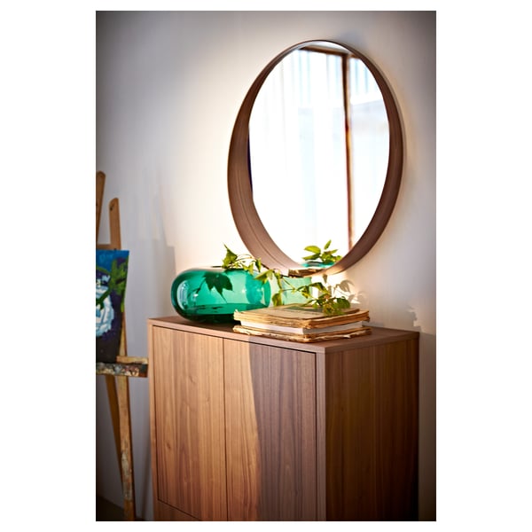 With STOCKHOLM walnut mirror, a window to your style. Circular wooden frame, glass, and shelf.