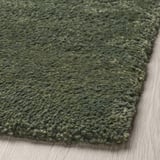Thick, soft green rug on wooden floor, showcasing high quality texture and craftsmanship.