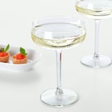 Two wine glasses filled with sparkling wine, accompanied by a small dish of dessert cups garnished with mint leaves.