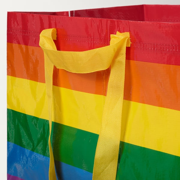 Bright rainbow-colored shopping bag with sturdy yellow handles, stylish and functional.