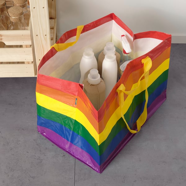 Rainbow-colored reusable tote bag holding laundry items, showcasing its spacious and versatile design.