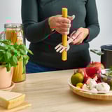 Person holding spaghetti server over table with ingredients.