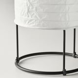 Black metal-framed table lamp with white rice paper shade, showcasing modern design and soft diffused lighting.