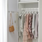 Open closet with clothes. Mirrored door reflects hanging garments.