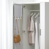 Mirrored wardrobe door revealing clothes and accessories, featuring hooks for bags and jewelry.