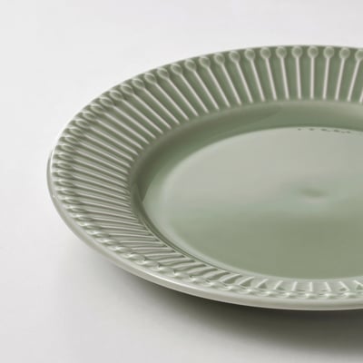 Four light green plates, three stacked, one flat, textured rim, ceramic.