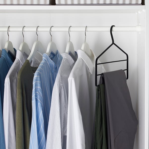 Wardrobe with neatly arranged shirts, pants. Black hanger keeps trousers in place, hangers have velvet surfaces to prevent marks.