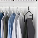 Wardrobe with neatly arranged shirts, pants. Black hanger keeps trousers in place, hangers have velvet surfaces to prevent marks.