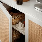 Open white cabinet showing wicker baskets and ceramic items.
