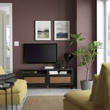 Modern living room with purple walls, yellow couch, plant, & mountain photos.