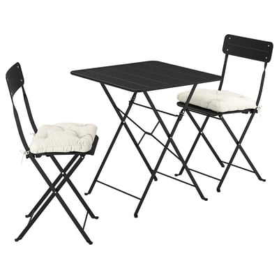 A black SUNDSÖ outdoor table and two chairs with beige cushions, neatly folded and ready for small spaces.