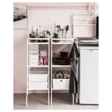 Modern kitchen corner: white SUNNERSTA shelf holds black plates, cups, glass jars, and pink bottles.