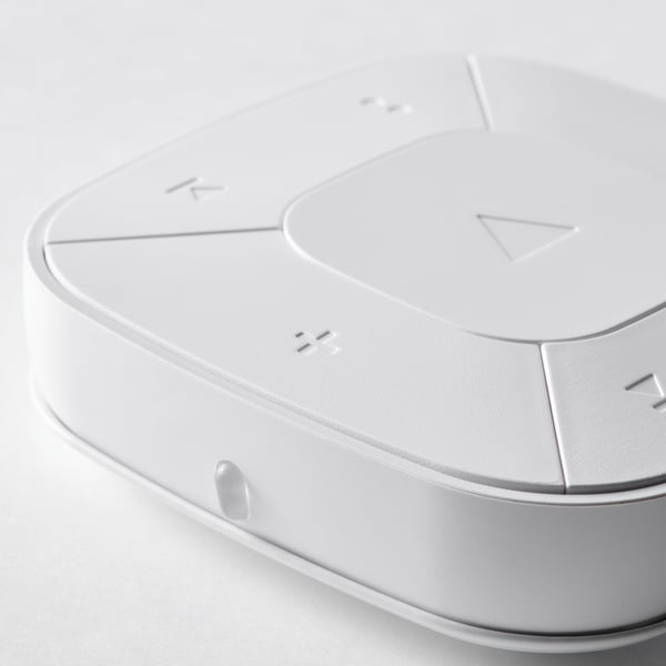 Modern white remote control with circular center button and minimalistic design.