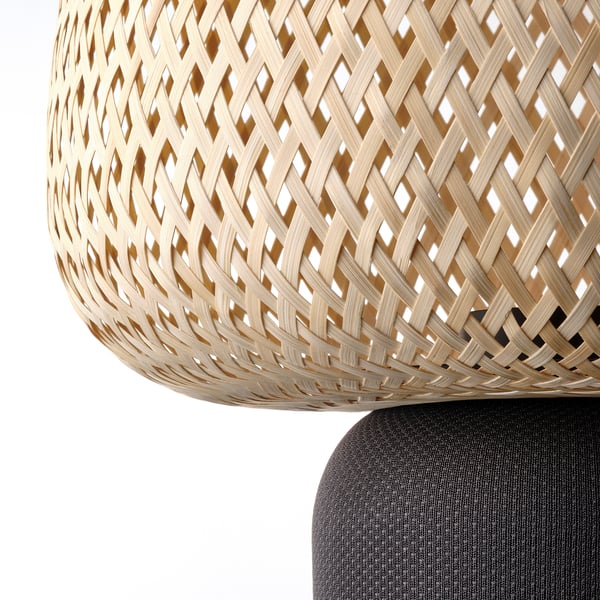 A wicker basket lamp with intricate, interlaced design and a sturdy base.