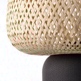 A wicker basket lamp with intricate, interlaced design and a sturdy base.