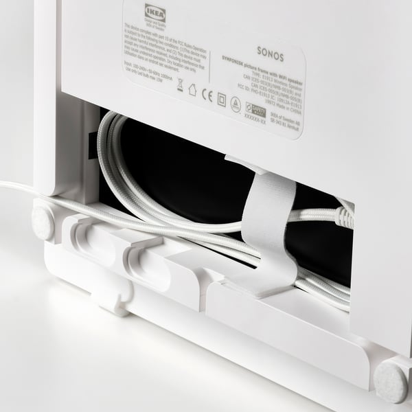 A modern, white ikea SYMFONISK wifi speaker in pristine condition, partially unboxed with visible cords and packaging.