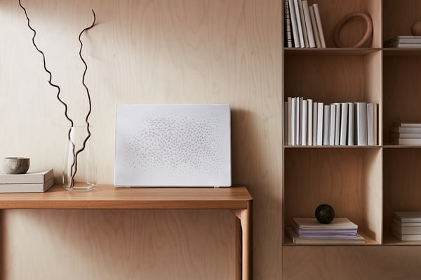 Modern living room setup with SYMFONISK wifi speaker, white, on wooden shelving.