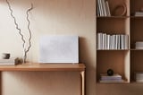 Modern living room setup with SYMFONISK wifi speaker, white, on wooden shelving.
