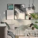 Modern gray living room with ikea picture speaker, nature posters, hanging bulbs, green-cushioned sofa, and plants.