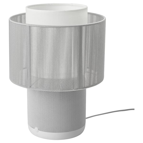 A white SYMFONISK lamp with fabric cover and cylindrical shape, its a wifi speaker with integrated lighting.