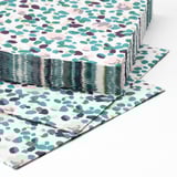 Stacked, colorful, patterned paper napkins with abstract shapes. Three-ply design ensures high absorbency. Bright and inviting for table settings.