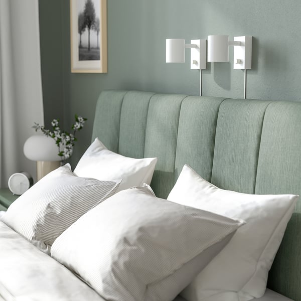 Calm bedroom with TÄLLÅSEN bed, plush grey-green headboard, crisp white linens, sleek wall lamps, soothing decor.