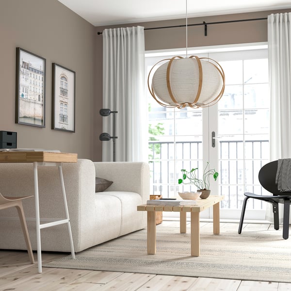 Modern living room with light furniture, TAGGTOFS lamp, and balcony view.