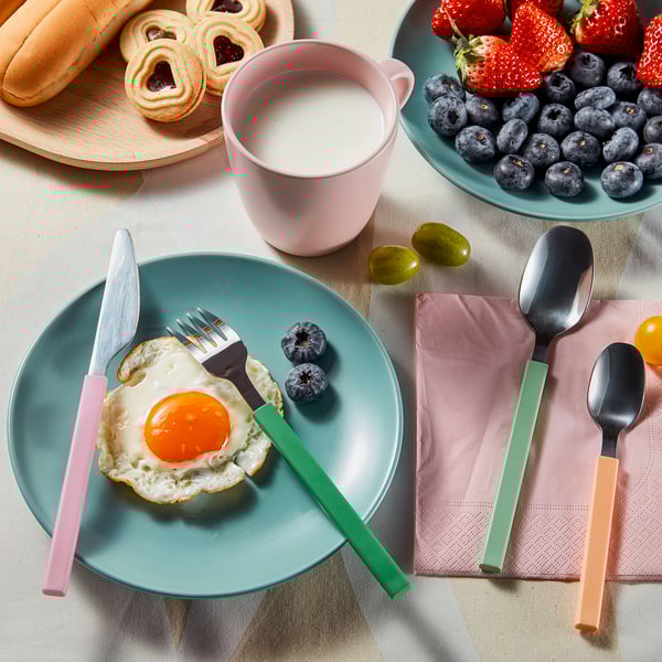 Colorful cutlery set with plates, berries, and breakfast. Bright handles enhance table settings mood.