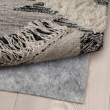 Rug with fringe on wooden floor.