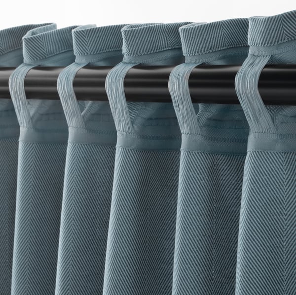 Gray curtains with herringbone pattern hang from black rod using hooks, designed to block light and ensure privacy.